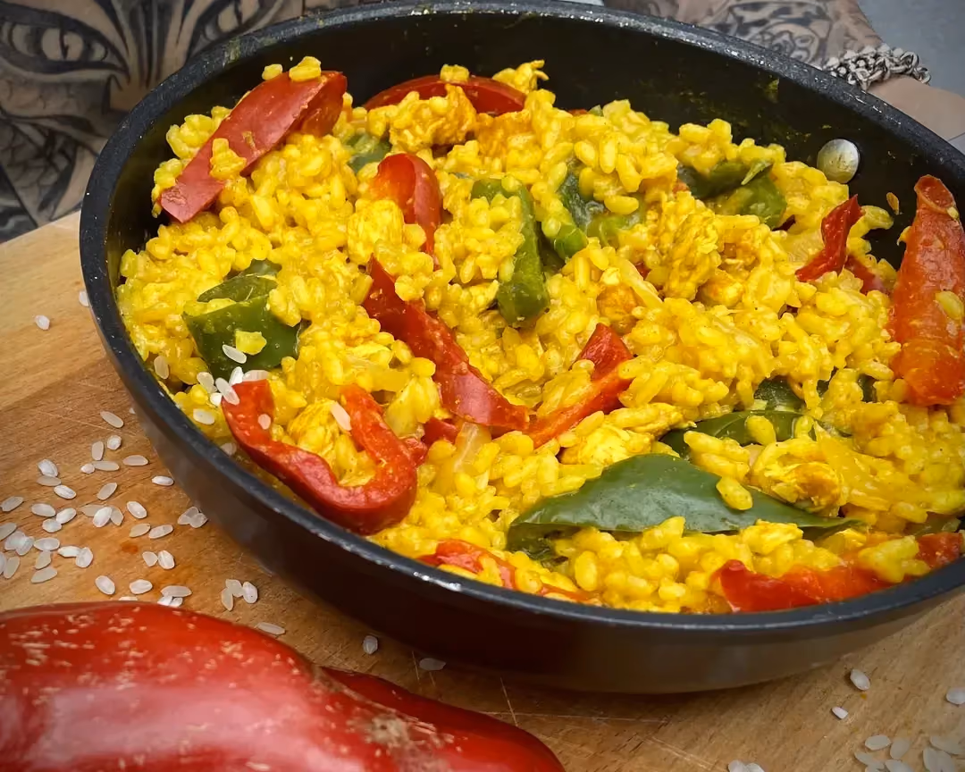 Dans un grand plat ovale de couleur noir se trouve le riz coloré par le curcuma. Les poivrons verts et rouges apportent de belles couleurs à ce plat.