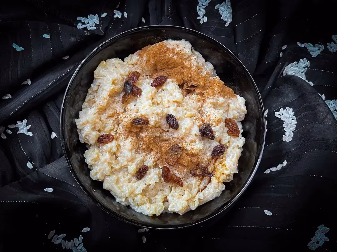 Dans un grand bol se trouve le riz au lait. Le topping est composé de raisins de Corinthe.