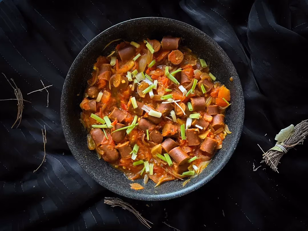 Le rougail saucisse végétarien est présenté dans un saladier profond de couleur bleu.