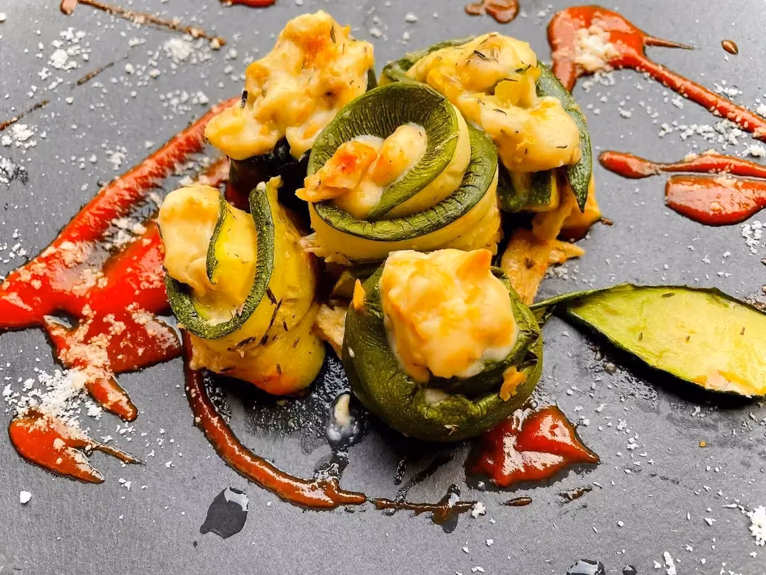 Zucchini rolls are arranged on the gray baking sheet. A beautiful harmony of colors for this flavorful dish.