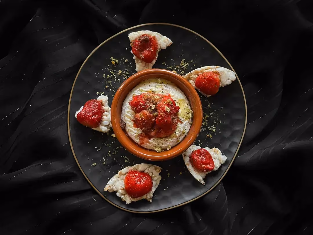 The roasted Saint-marcellin with strawberries is placed in the center of a blue honeycomb-patterned bowl.