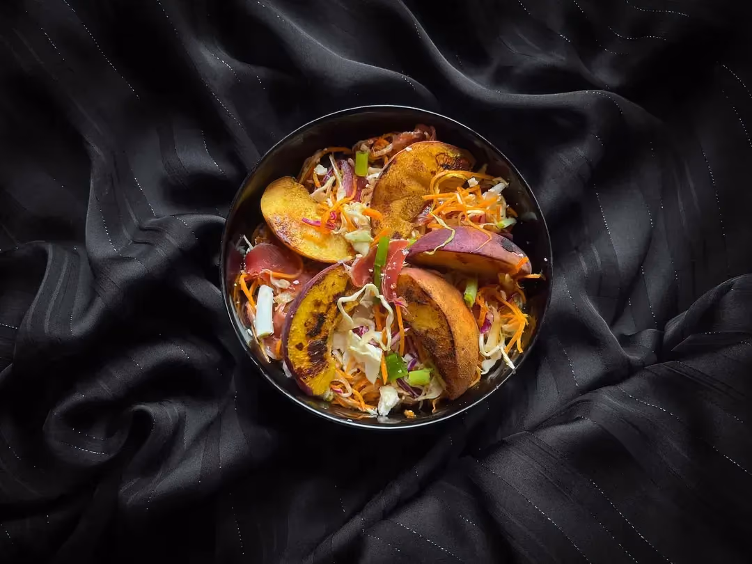 This salad is made with grilled peach wedges, feta, shredded red and white cabbage, and Serrano ham.