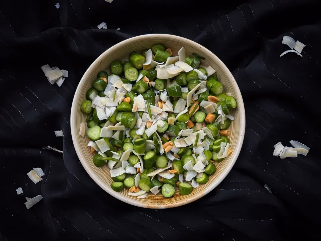 A small beige stoneware bowl holds the cucumber, peanut, coconut, and chicken salad.