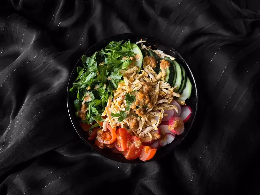 Cette salade de crudité est composée de concombres, tomate cerise, radis, purée de cacahuètes et tofu râpé.