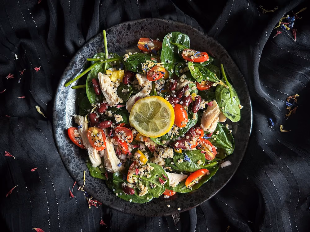 Dans un saladier en verre fumé, la salade de haricots rouges poulet et quinoa montre ses jolies couleurs.