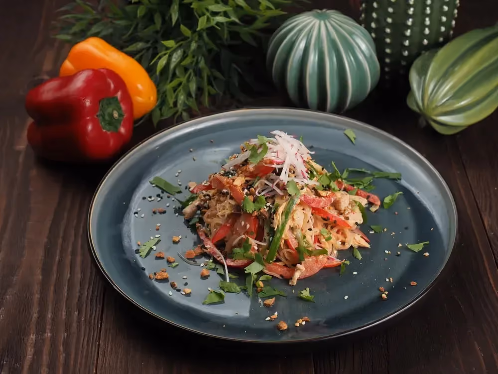 In a large round green dish, the ingredients, konjac noodles and salmon, are arranged in a pyramid shape.