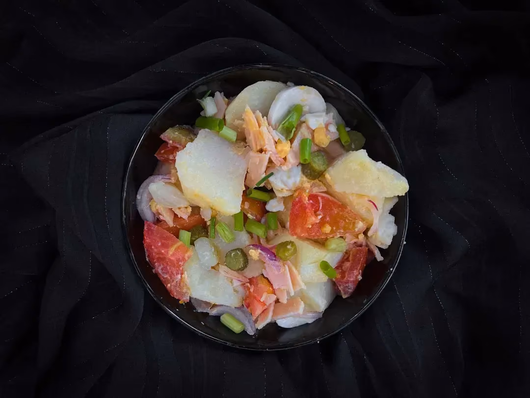 Dans un petit saladier sont mélangés les pommes de terre coupées en gros cubes, du blanc de dinde, du St Moret, des oeufs durs avec des cornichons.