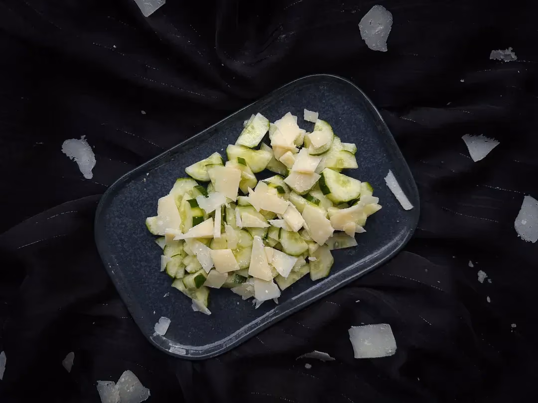 A rectangular blue earthenware dish holds the super simple cucumber and parmesan salad.