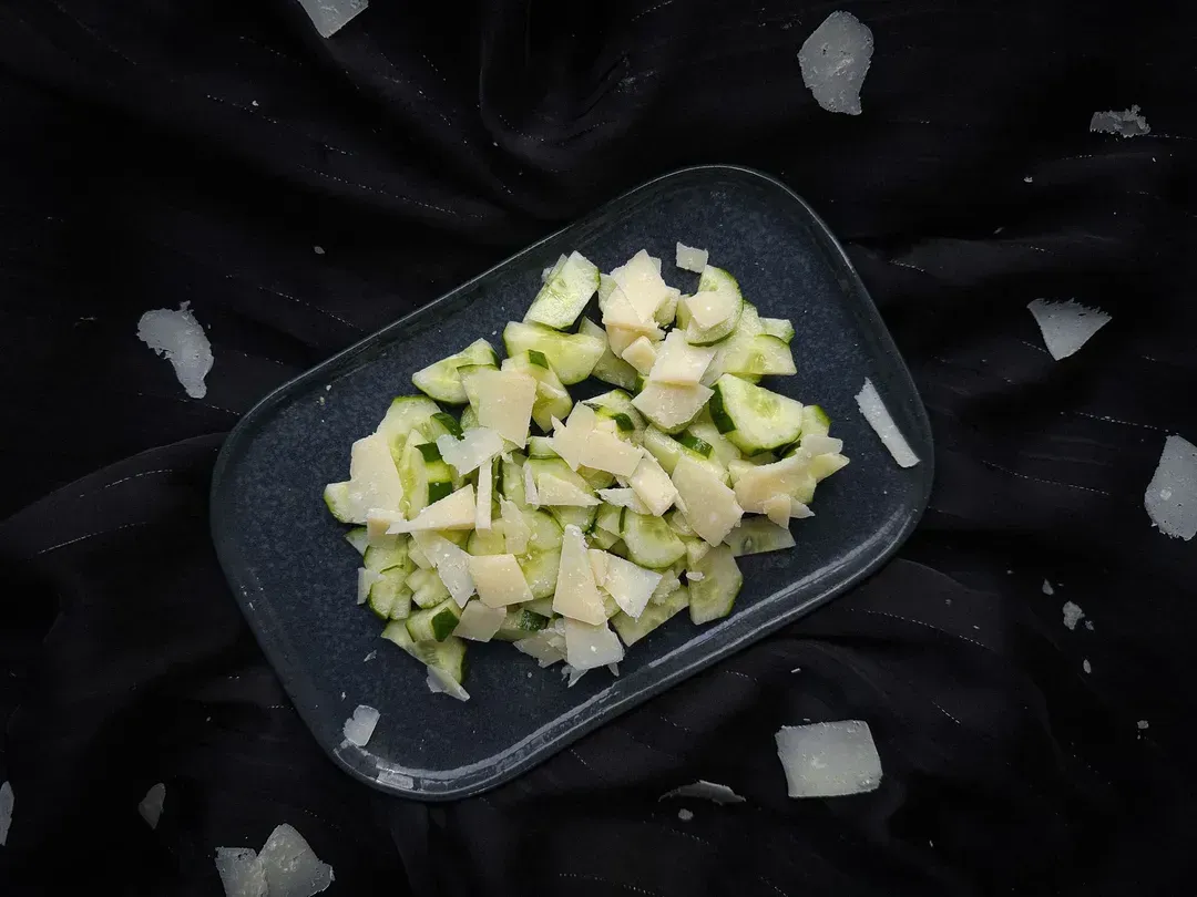 A rectangular blue earthenware dish holds the super simple cucumber and parmesan salad.