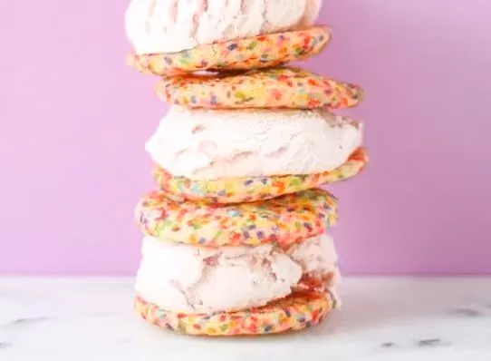 Des cookies couleur arc en ciel alternent avec de la glace parfum amande. ils sont empilés façon sandwich.