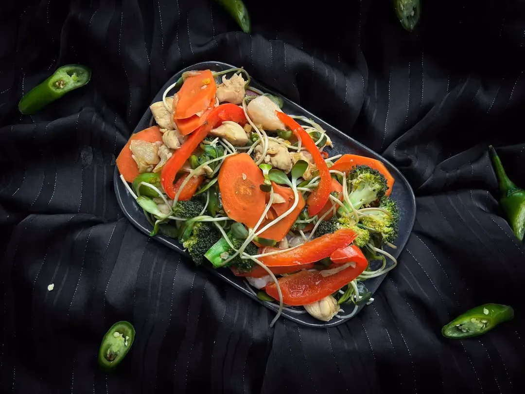 Les légumes et le poulet sont sautés préalablement, et ils sont présentés dans un bol bleu sur un set noir