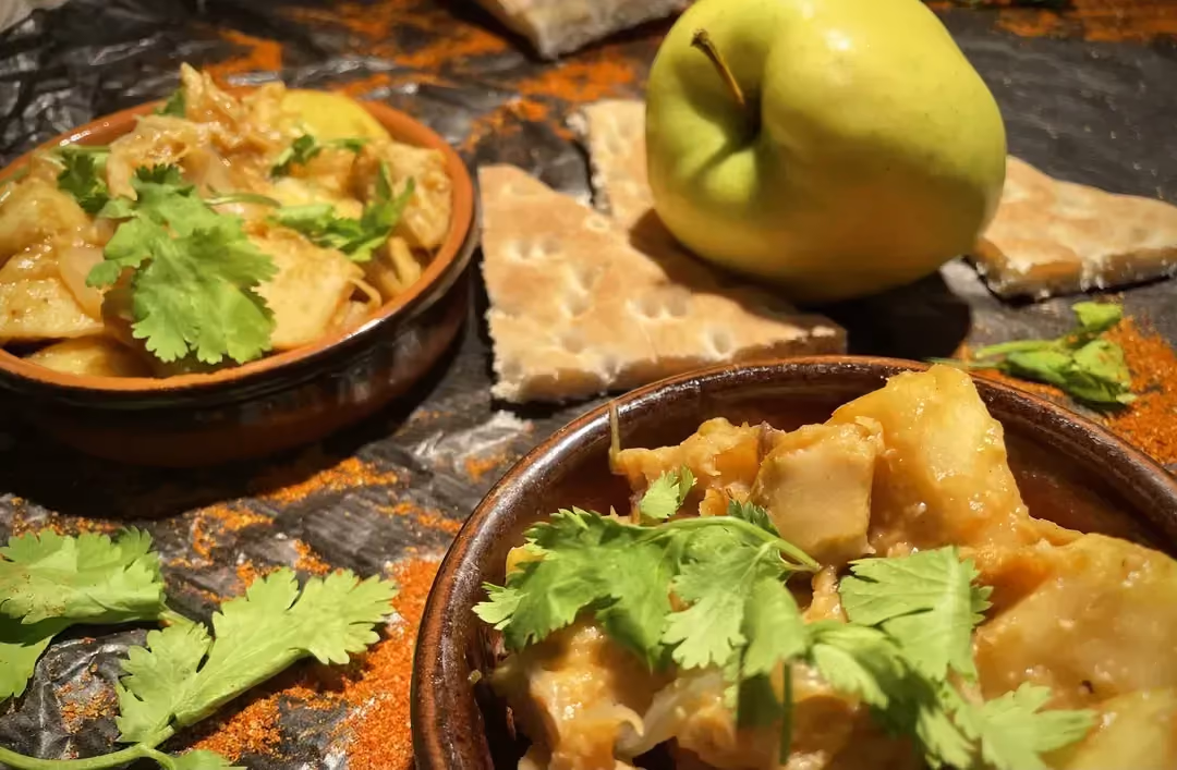 Le soja à l'indienne est présenté dans deux plats ronds en terre cuite. Sur la table on peut voir une belle pomme verte.