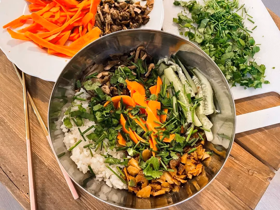 In a large bowl, the rice is arranged at the bottom and topped with the vegetables. Parsley and chopped chives accompany this recipe.