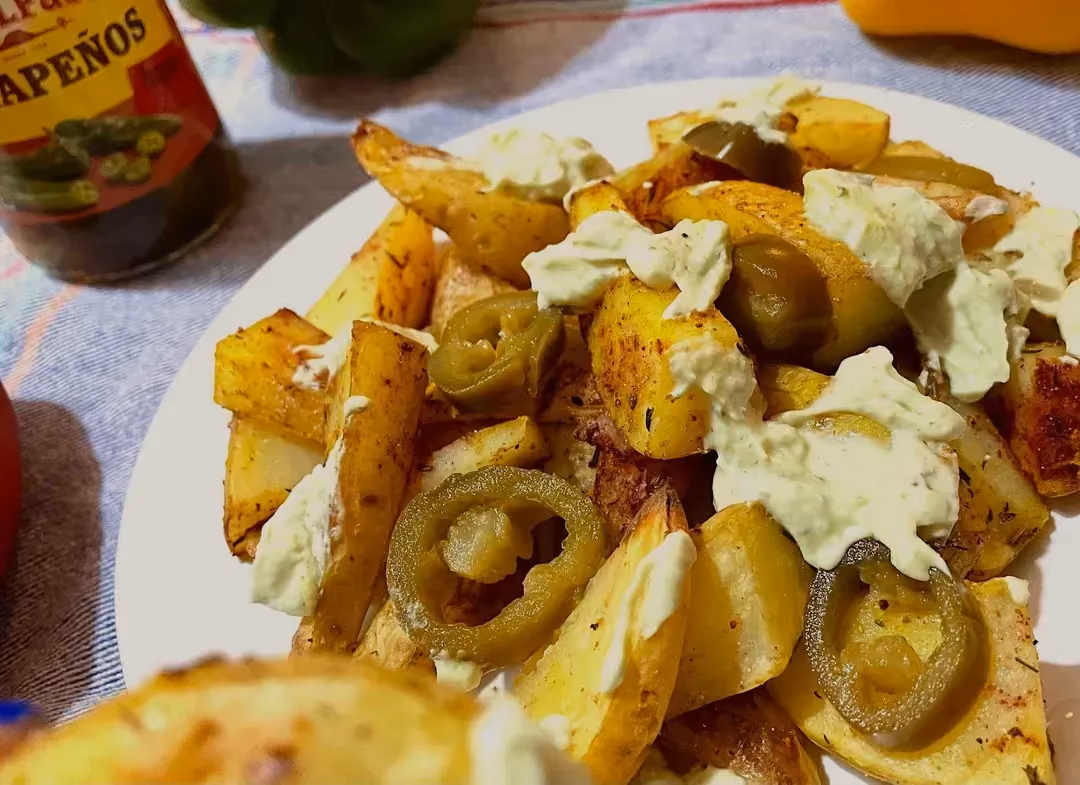 Disposées sur une assiette blanche les pommes de terre sont coupées en gros morceaux. Le piment Jalapeno et le St. Moret agrémentent le tout.