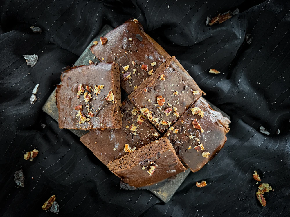 The protein brownie is presented in the shape of a stunning pyramid! Nuts are visible near the dessert.