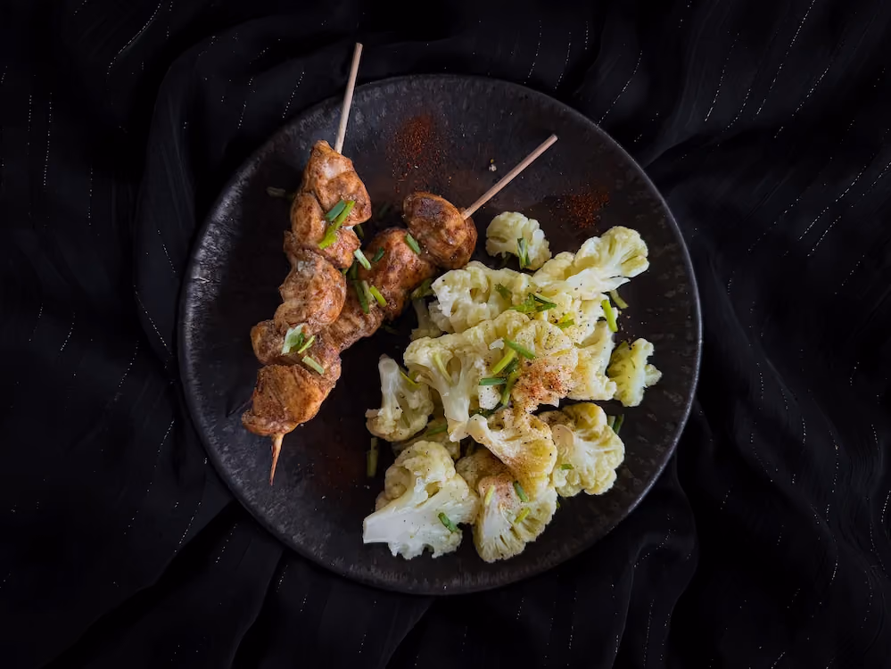 Trois généreuses brochettes de poulet à la marocaine bien grillées sont accompagnées par le choux fleur servi à part.