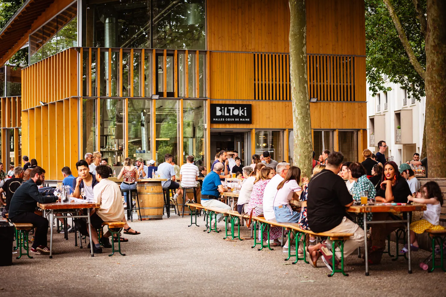 Terrasse animée des Halles Cœur de Maine à Angers avec des visiteurs attablés devant le bâtiment Biltoki
