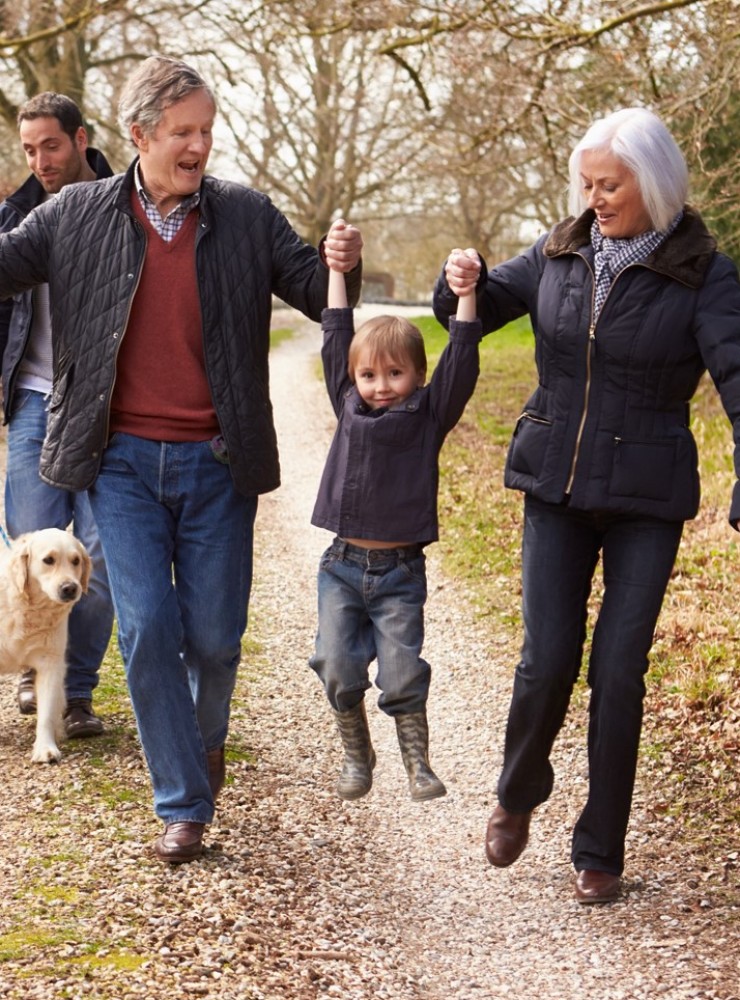 Multi-generation family walking together on country path with dog