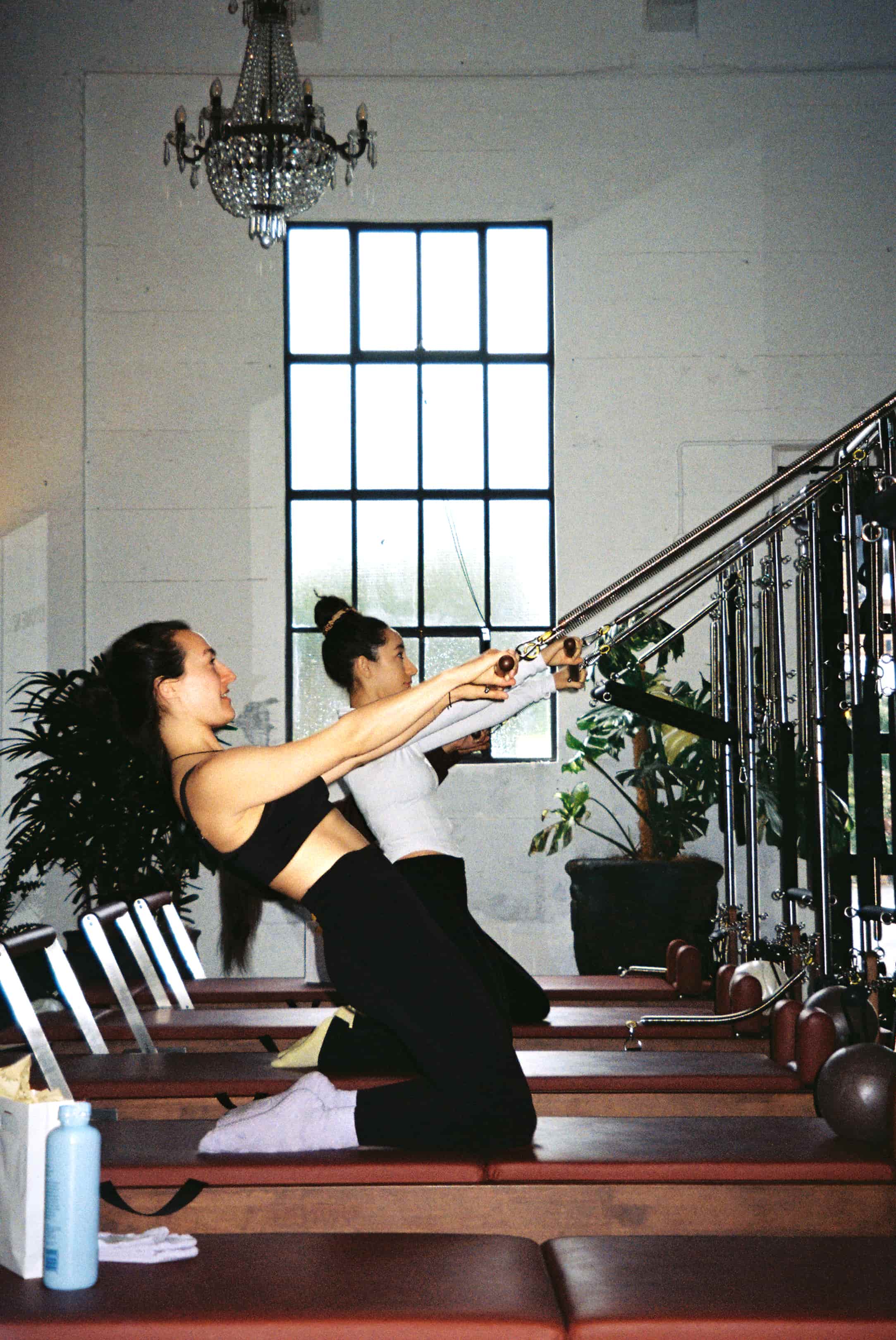 Instructor demonstrating tower Pilates, deep hamstring exercise achieved by using tower for support. 