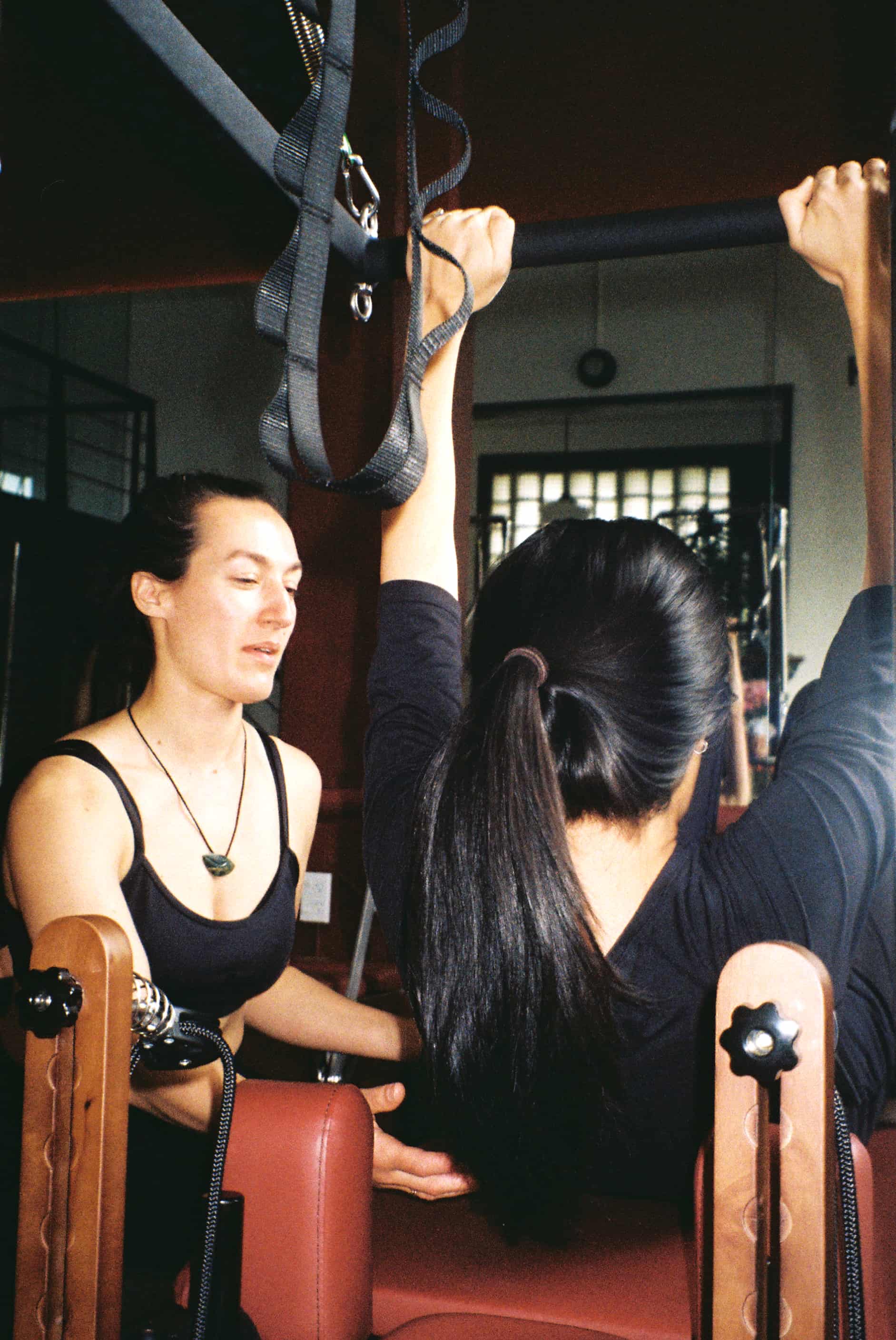 Instructor being hands on during pilates class with a client adjusting form.