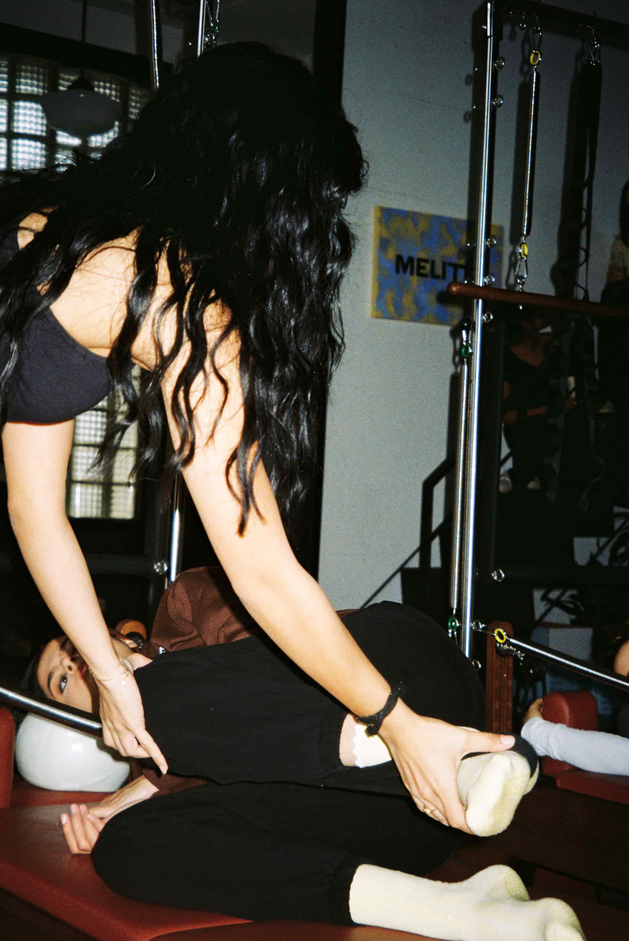 Instructor hands on with client doing Pilates to help them with their form.