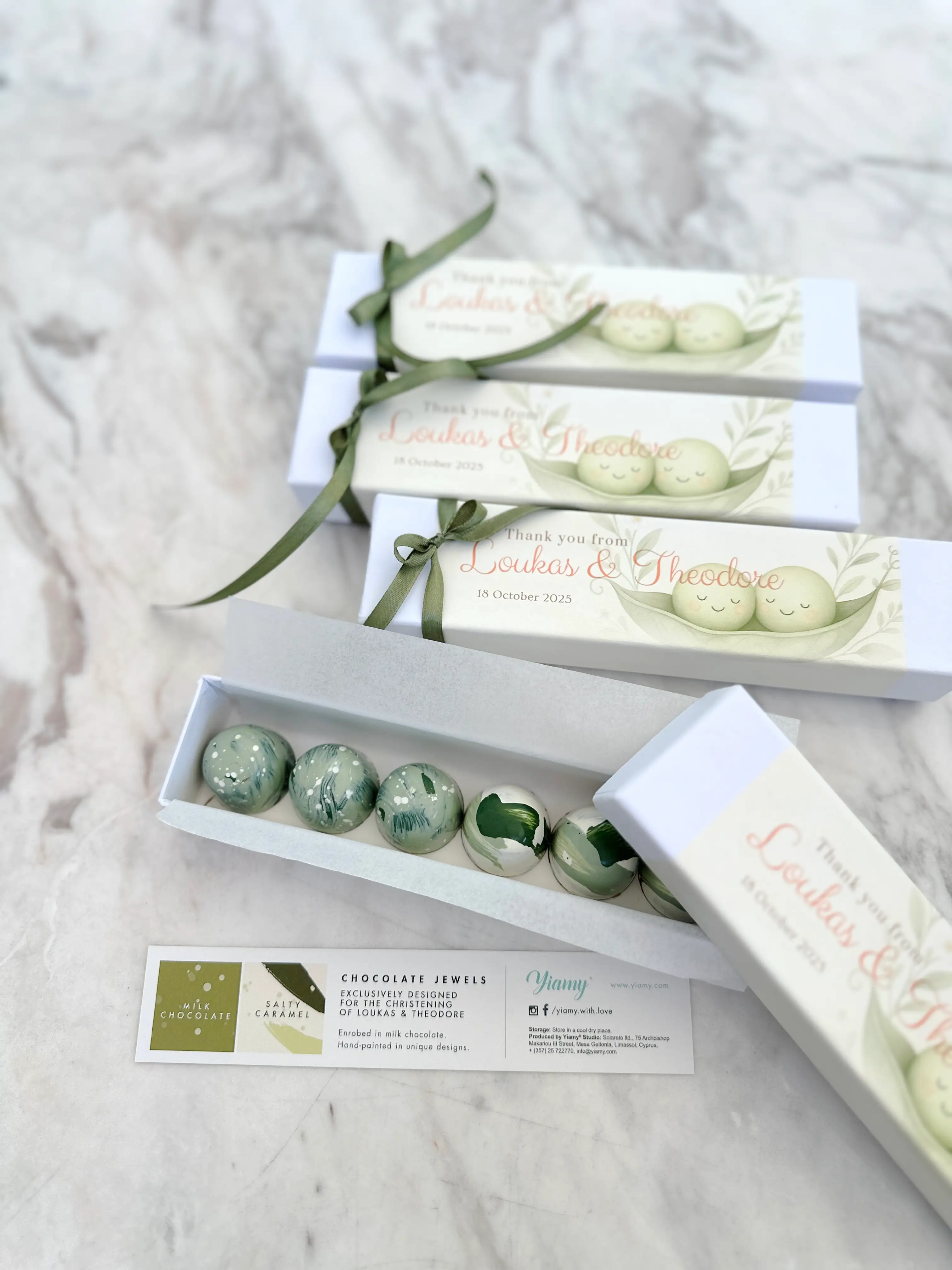 Elegant chocolate bonbon gift boxes for christening, custom-designed “two peas in a pod” theme favours with hand-painted chocolates, personalised packaging, and luxury ribbon detailing in soft green tones