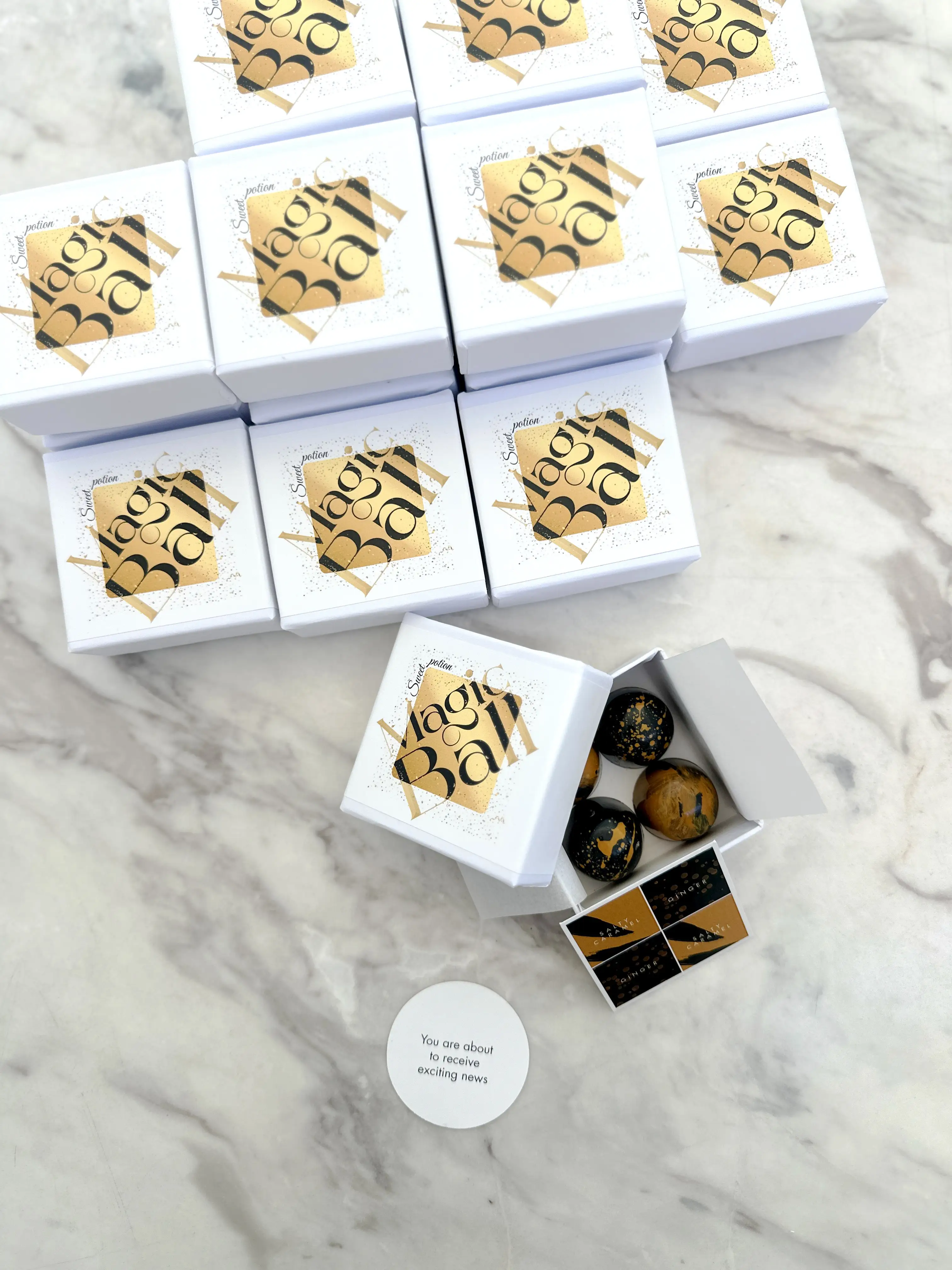 Premium “magic ball” chocolate bonbon gift boxes with black and gold design, filled with handcrafted chocolates and accompanied by a message card, created as sophisticated corporate gifts for special announcements