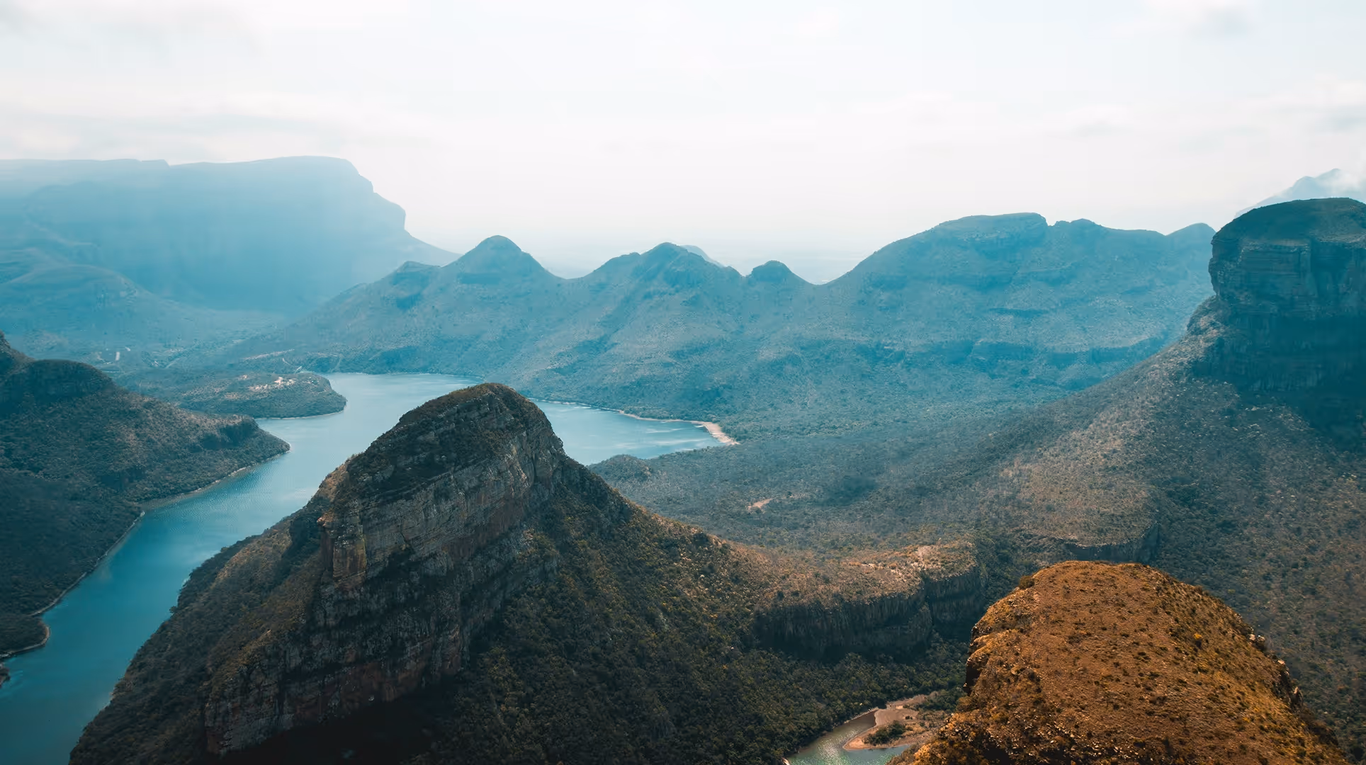 A winding river flowing through rugged mountainous terrain under a cloudy sky.