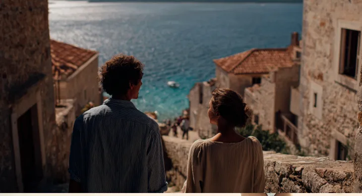Two people walking down stone steps toward the sea.