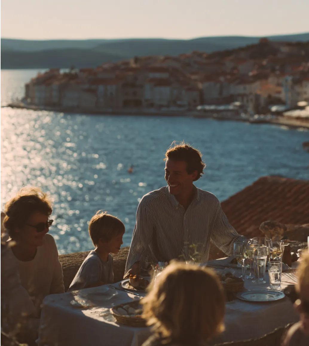 A family eating together outdoors with the sea in the background.