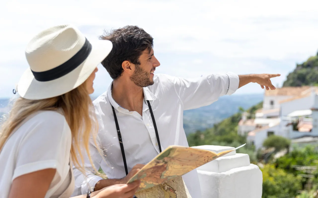 A man and woman outdoors looking at a map while he points toward the landscape.