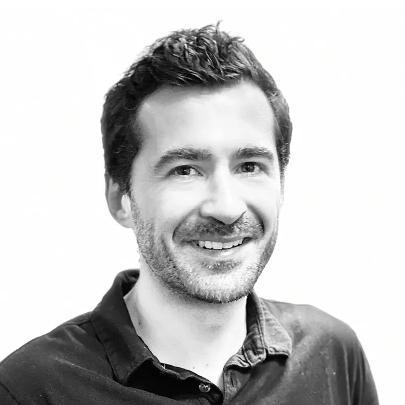 Portrait en noir et blanc d'un homme souriant avec une chemise à col.