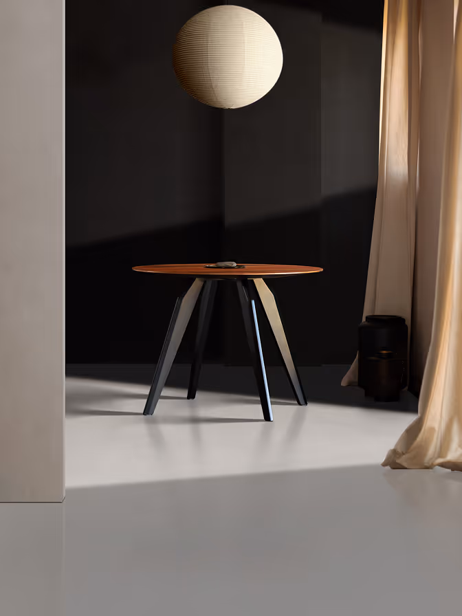 Jowisz table in Indian apple veneer with black enamel legs, photographed against a dark wall