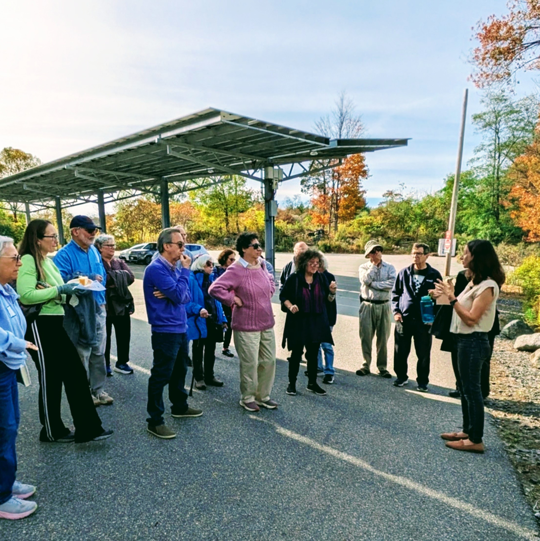 A group stand in a circle in front of solar panels