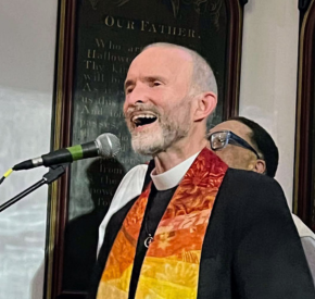 Rev. Fred Small singing into a microphone at the Green Light for Climate Justice event
