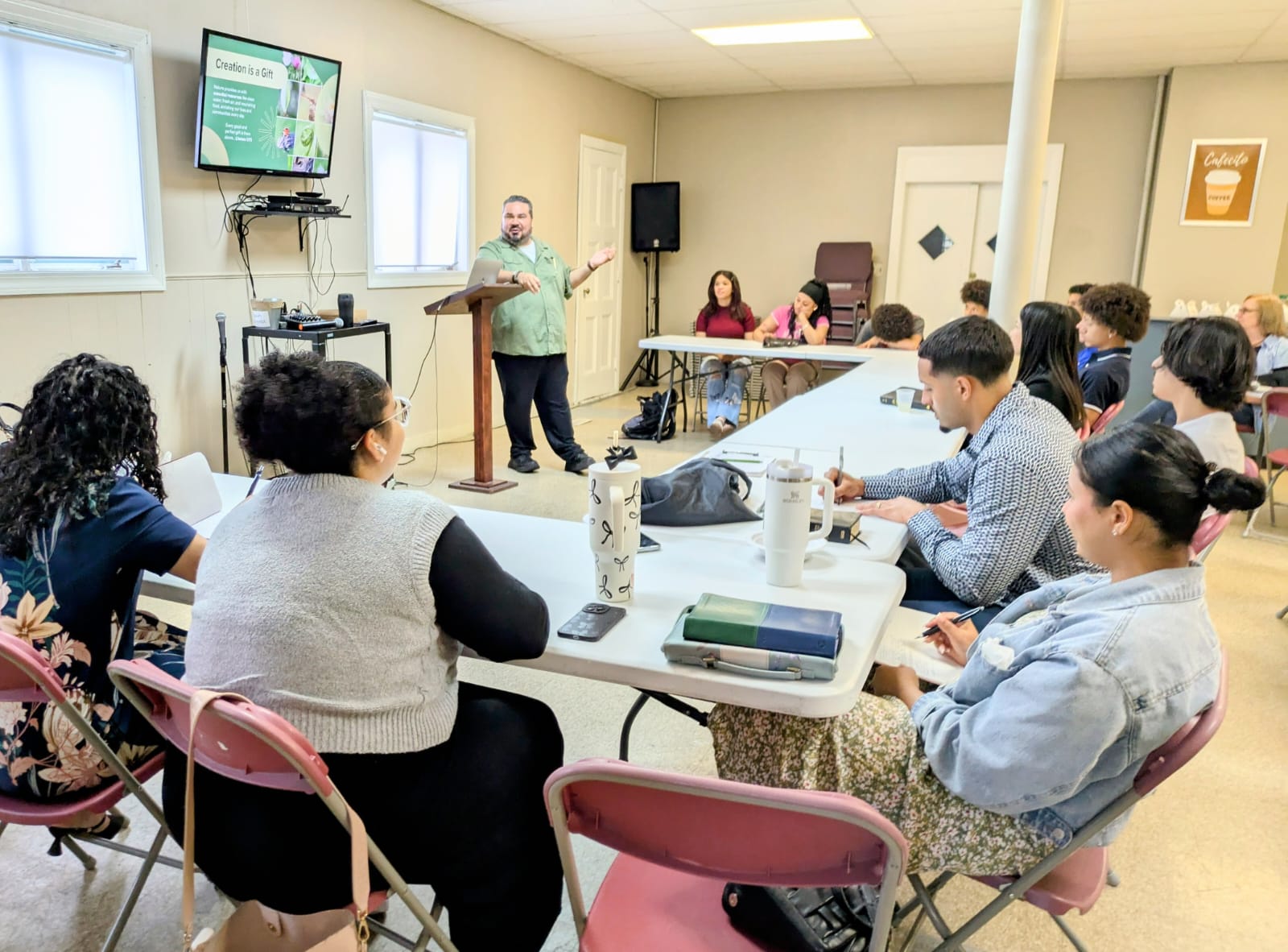 MassIPL's Javier Roche teaching with a screen while Youth Climate Ambassadors listen and take notes in a classroom setting.