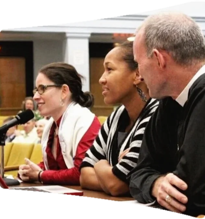 Shoshana Meira Friedman, Mariama White-Hammond, and Fred Small testify at a public hearing on climate policy. They are seated at a table speaking into a microphone, engaged in discussion.