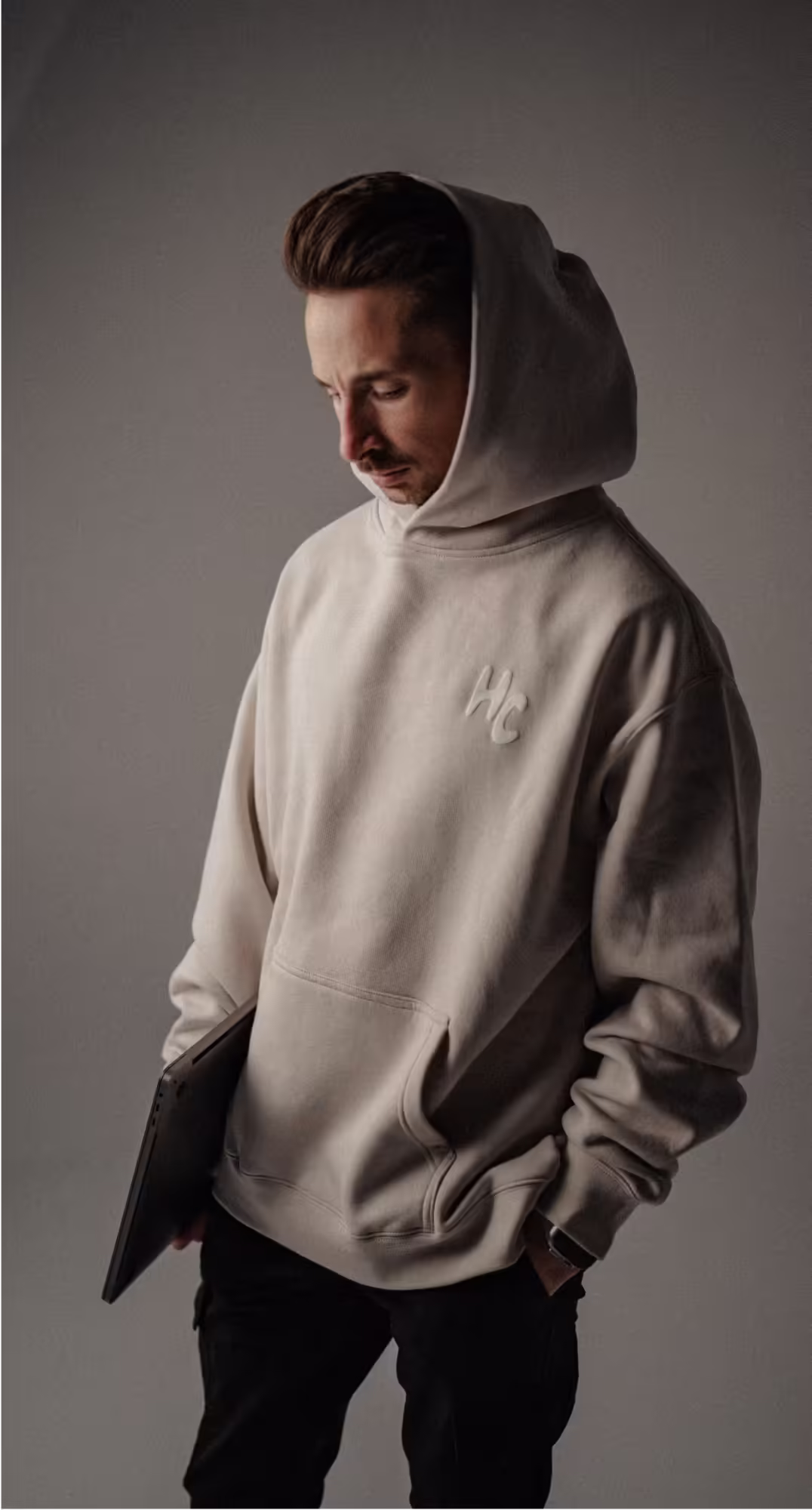 a man in a white hoodie holding a laptop