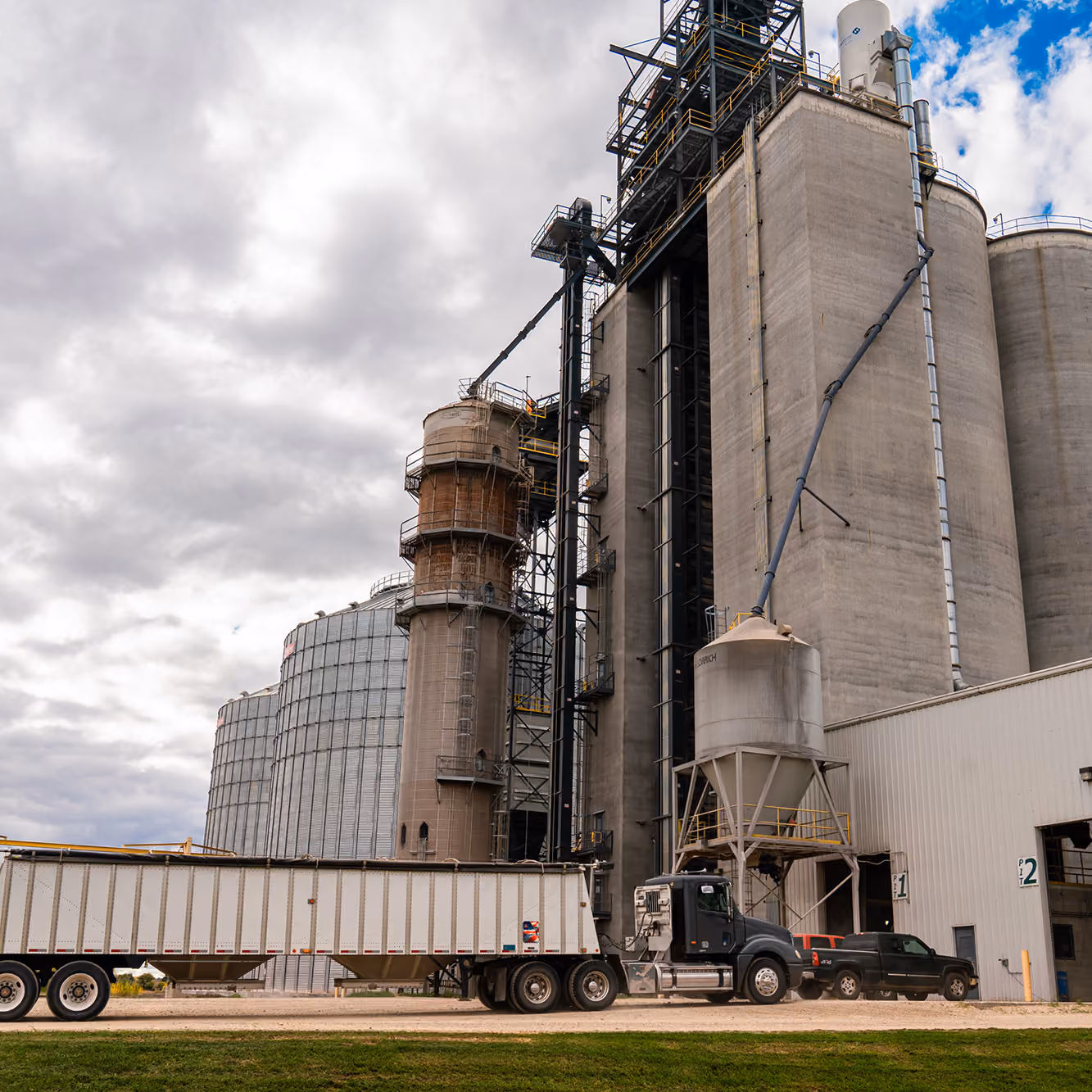 Grain elevator and truck under a cloudy sky