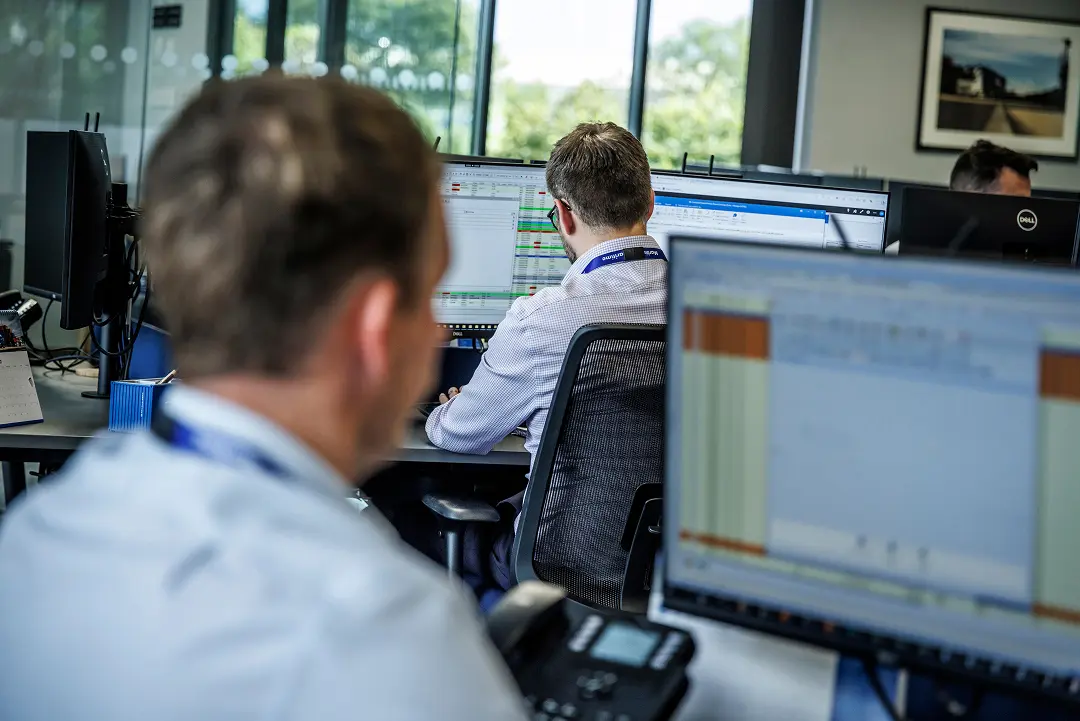 Two employees at their desks, looking at computers