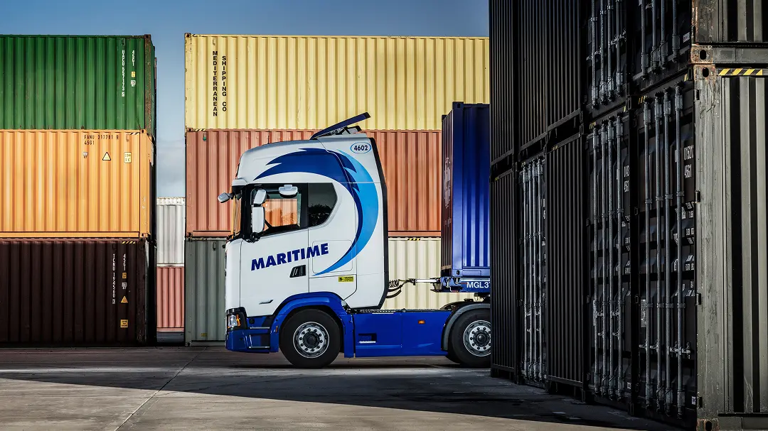 Maritime Transport branded HGV driving through a container yard