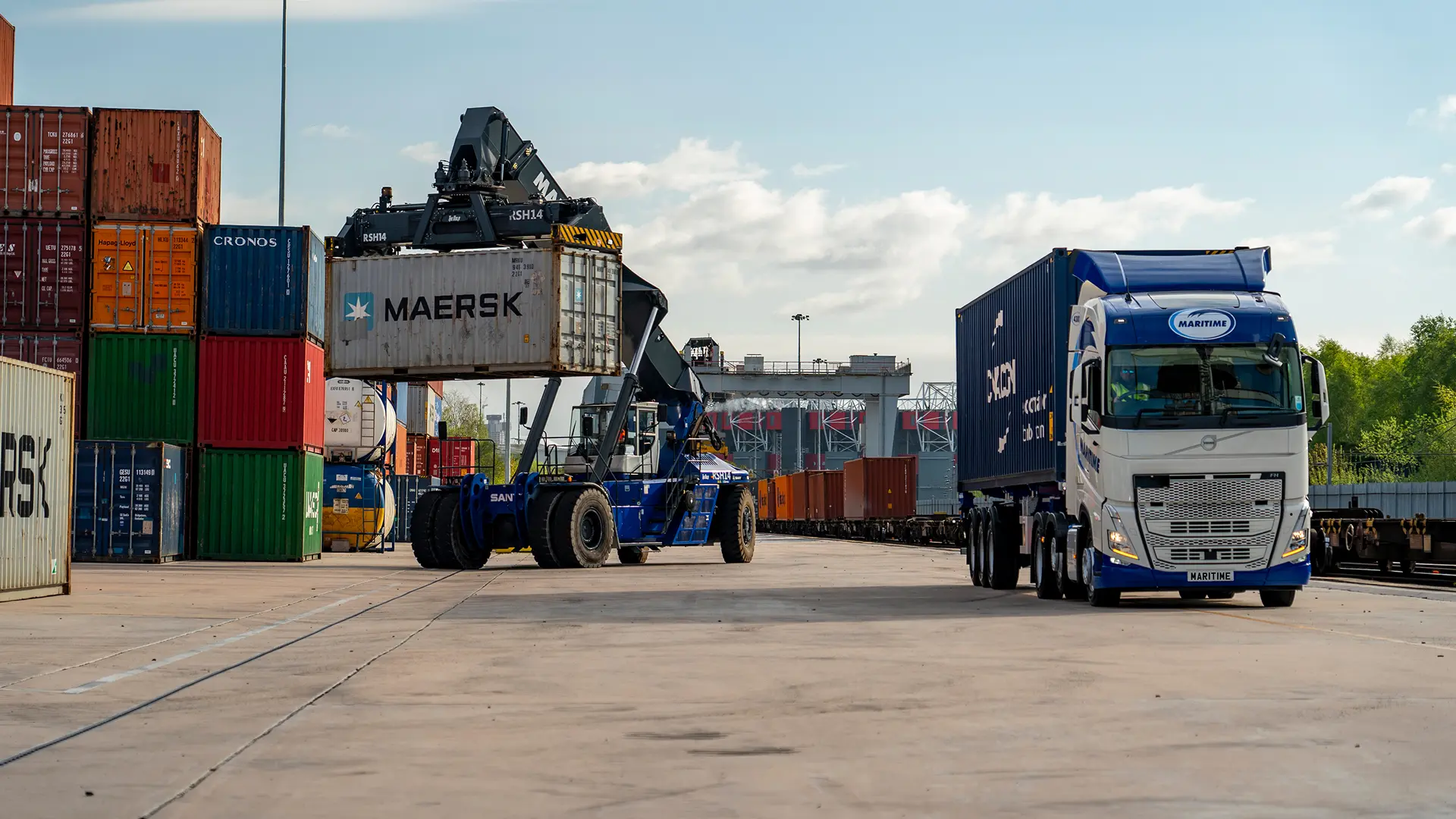 Container truck drives alongside a reachstacker that is moving a container