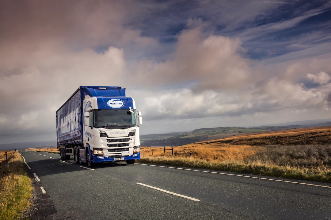 Maritime Transport curtainsider on the road with blue skies in the background.