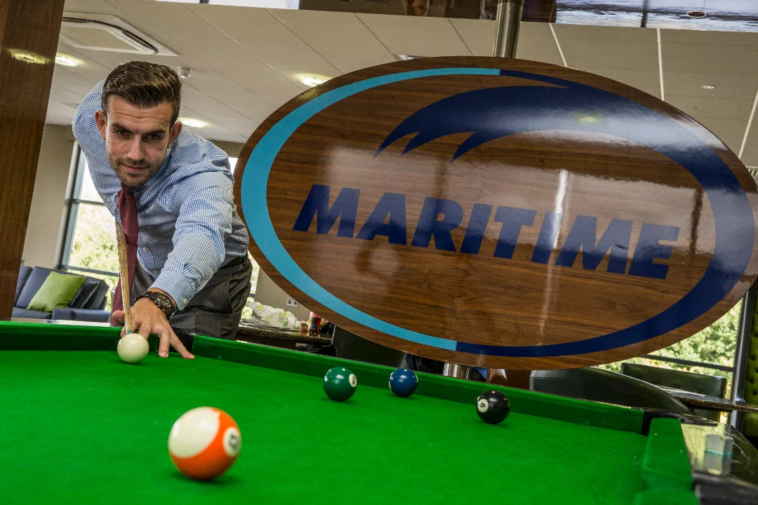 An office employee plays pool in a Maritime Transport building.