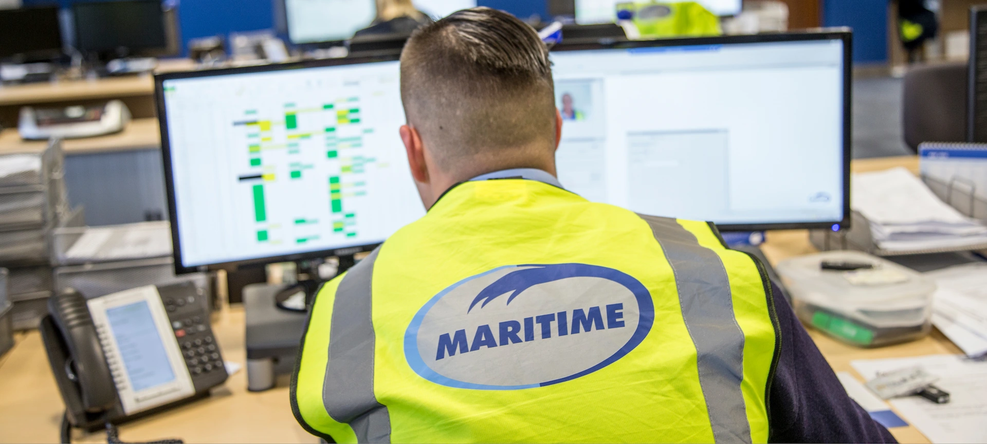 A Maritime Transport employee sits at a computer working.