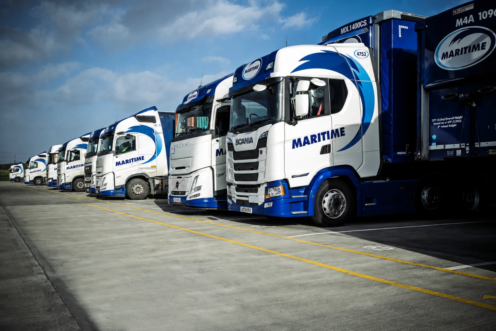 Row of Maritime Transport branded vehicles in a transport depot.