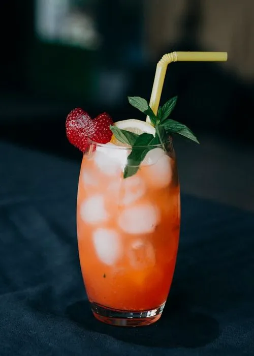 A drink with strawberries and ice in a glass.