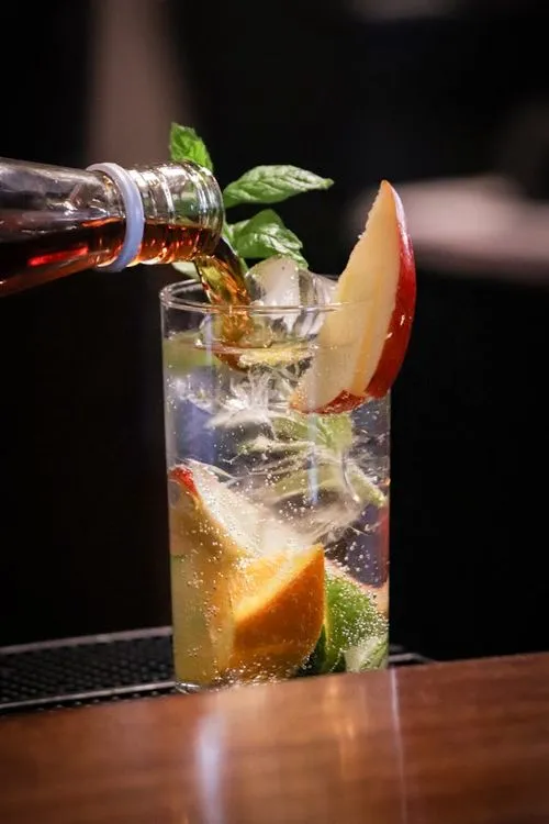 A glass filled with water and fruit on top of a table.