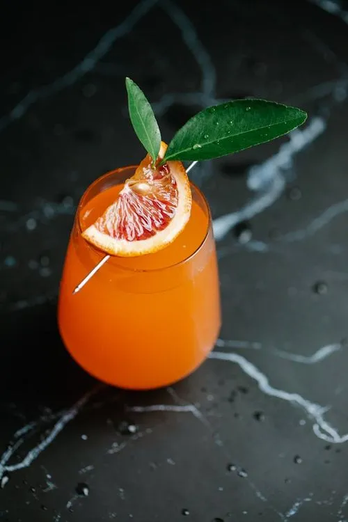 A grapefruit cocktail garnished with a green leaf.
