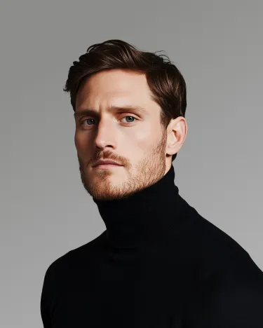 A man wearing a black turtle neck sweater.
